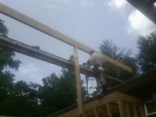 Carpenter setting a ridge beam over a new addition frame — Ice Dam Removal by Roofing Brothers in Baskerville