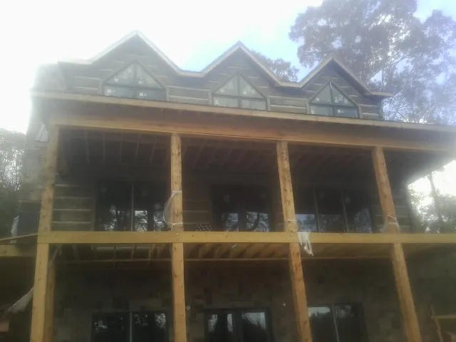Dormers and porch framing on a large log home under construction — Roof Coating work by our crew in Baskerville