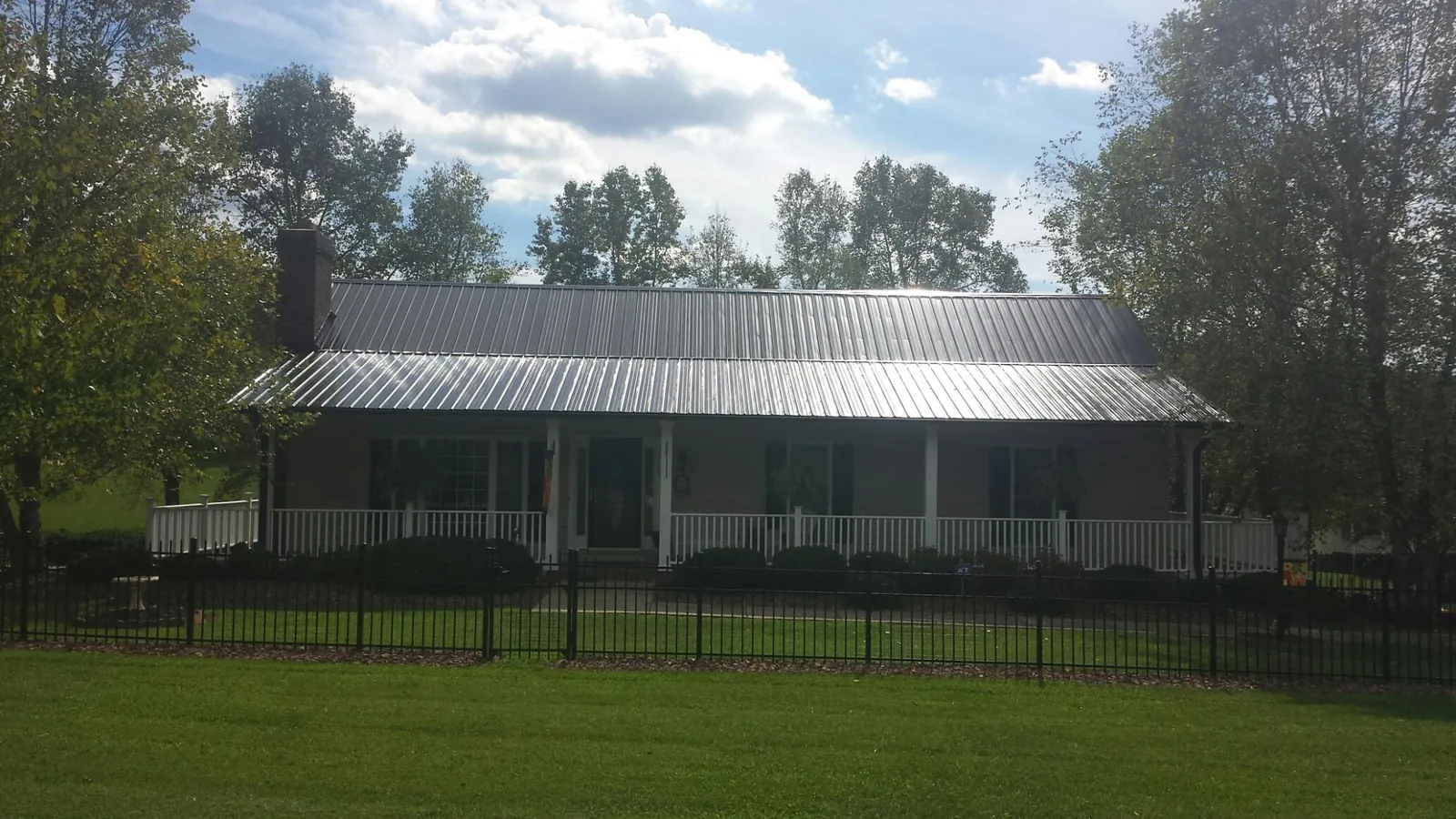 Gray metal roof on a brick ranch with a full width front porch — Gutter Guard Installation work by our crew in Baskerville