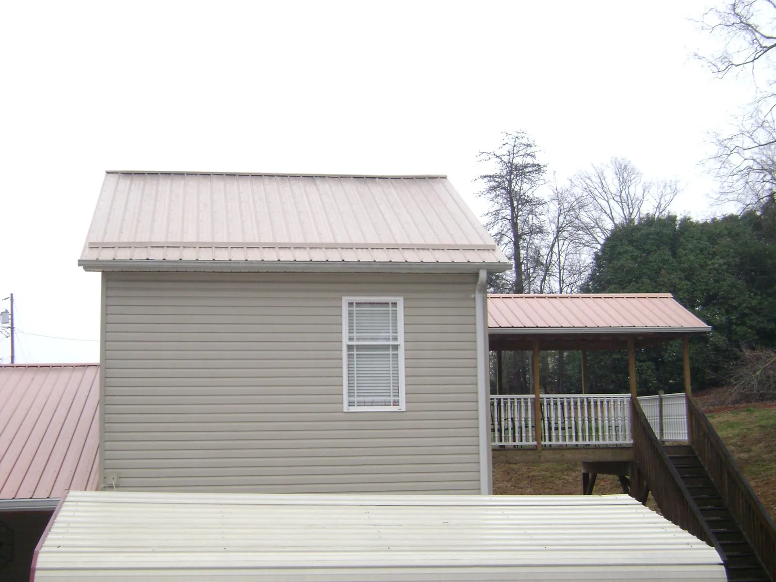Tan metal roofs on a two story addition and attached porch, from a Roof Replacement job in Baskerville