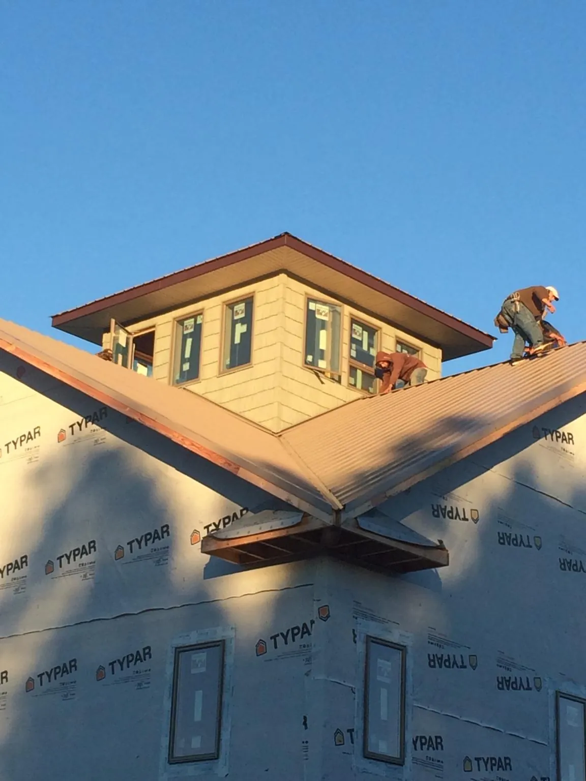 Roofers working around a rooftop cupola on a new metal roof at sunset — Roof Waterproofing in Baskerville by Roofing Brothers